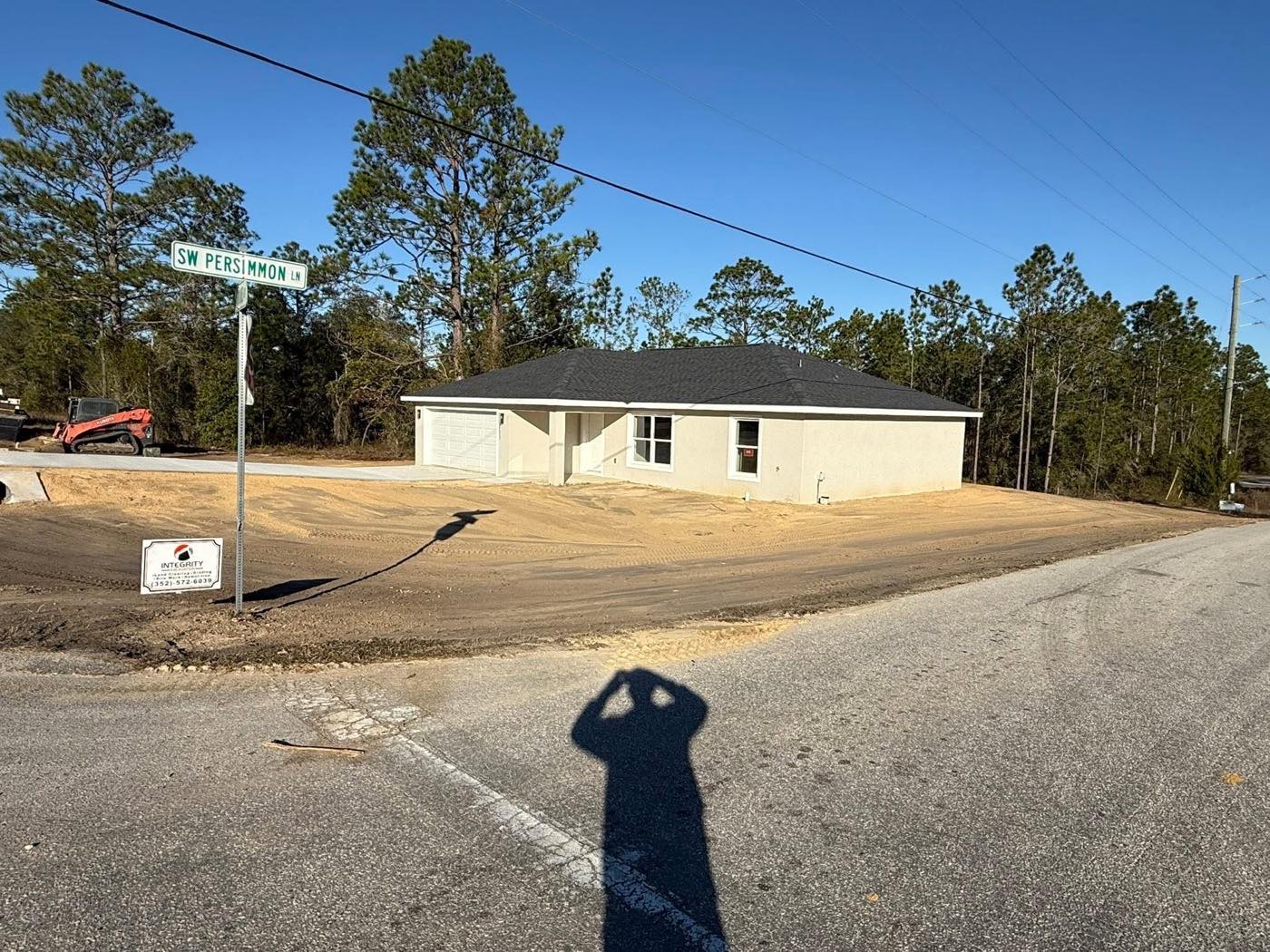 Finish-graded new home site by Integrity Excavation & Land Clearing in Ocala, FL, with company yard sign and skid steer