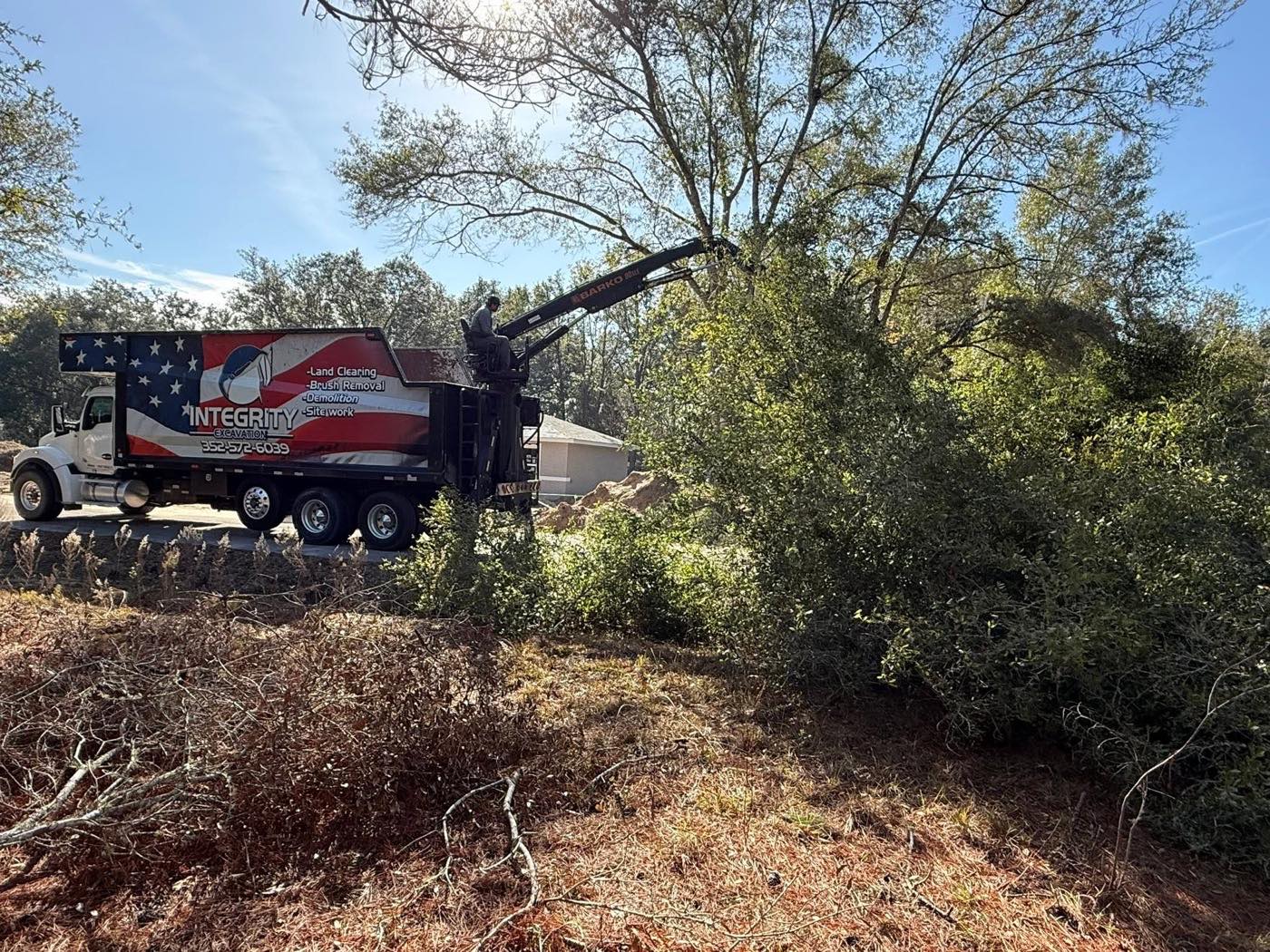 Integrity Excavation grapple truck removing cleared brush and trees from a lot in Ocala, FL